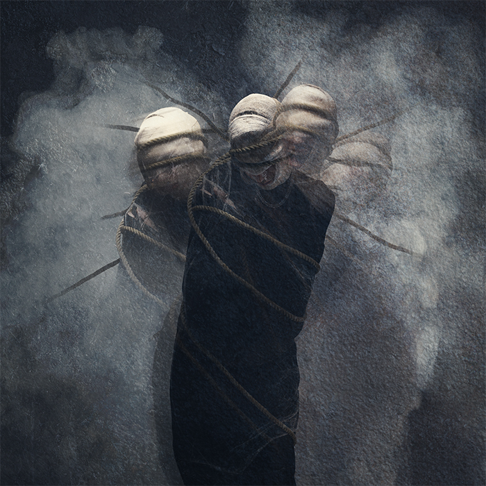 Multiple exposure of figure in darkness bound with ropes and bandages.